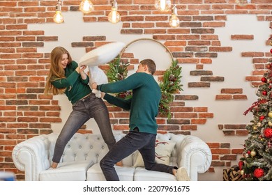 White Sofa. Concept Of Family, Christmas And Winter Season. Couple Have Fun And Do Pillow Fight In Room. Christmas Decor.