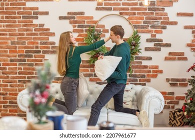 White Sofa. Concept Of Family, Christmas And Winter Season. Couple Have Fun And Do Pillow Fight In Room. Christmas Decor.