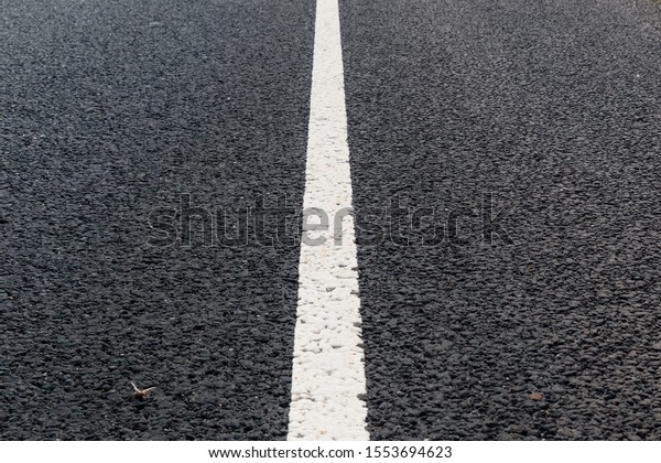 White solid\
line. Road marking on an asphalt\
road.
