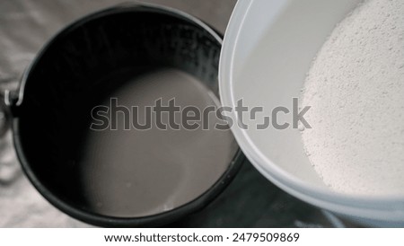 The white solution is poured into a bucket. Adding hardener to a bucket of plaster.