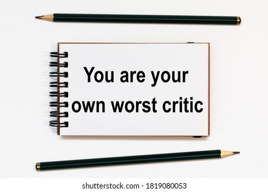 WHITE SPIRAL NOTEBOOK, TWO PENCILS WITH TEXT You Are Your Own Worst Critic