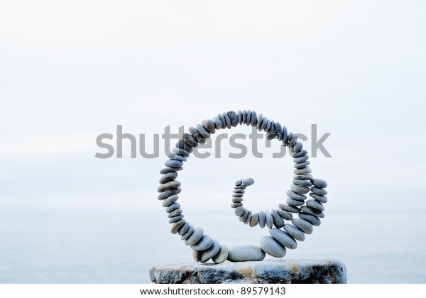 White spiral of pebbles on the boulder at the sea