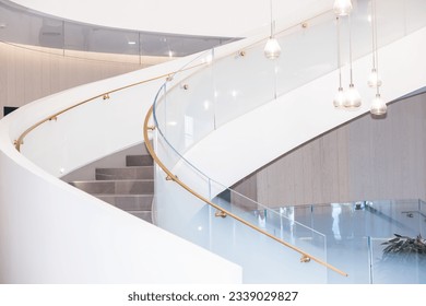 White spiral staircase with tempered glass railings and brushed gold handrail