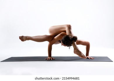 White Sporty Yogi Girl Doing Exercises, Asana Parivritta Eka Pada Koundinyasana, Twisted One Legged Arm Balance Posture, Yoga Pose, Studio White Background