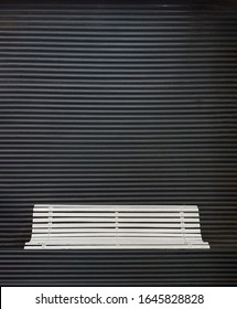 White square bench in front of closed metal curtain