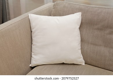 White square canvas pillow mockup on cozy couch, small cotton cushion mockup in living room interior., space for design presentation.