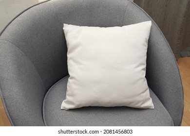 White square canvas pillow mockup on grey armchair, small cotton cushion mockup in living room interior.	