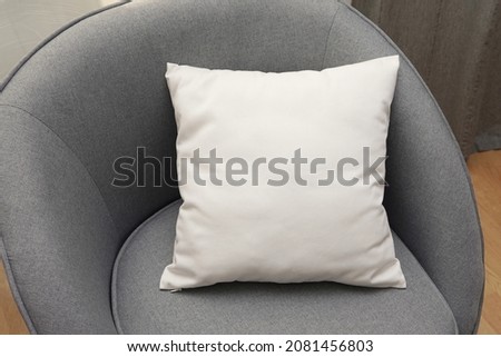 White square canvas pillow mockup on grey armchair, small cotton cushion mockup in living room interior.	