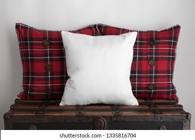 White Square Cushion Mockup With Two Red Plaid Square Cushions On Top Of An Old Vintage Suitcase.