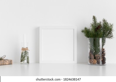 White Square Frame Mockup With A Bouquet Of Fir, Candle And A Gift On A White Table. Christmas Decoration.