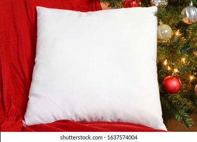 White Square PIllow Mockup Resting On Red Blanket With Lit Up Christmas Tree In Background