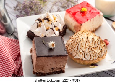 White Square Plate With Mini Sweet Cakes With Chocolate Mousse Cream Lemon Pai With Meringue Brownie With Bottle And Glass Of Milk Decorated With Dry Flowers