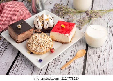 White Square Plate With Mini Sweet Cakes With Chocolate Mousse Cream Lemon Pai With Meringue Brownie With Bottle And Glass Of Milk Decorated With Dry Flowers