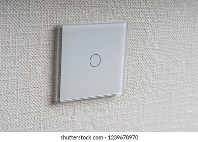 white square touch switch on white textured wall