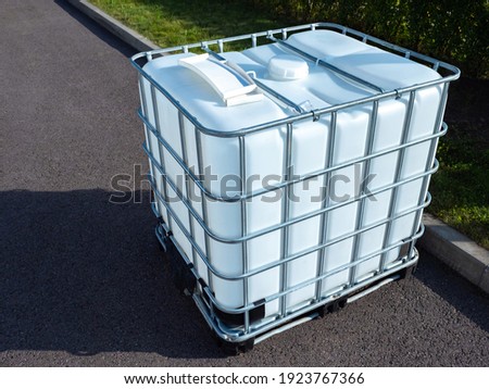 White square water tank. Water tank with metal grate. White huge container for liquid. Large water tank is outside. Сoncept is use of a container for liquid. Liquid reservoir reinforced a metal grid