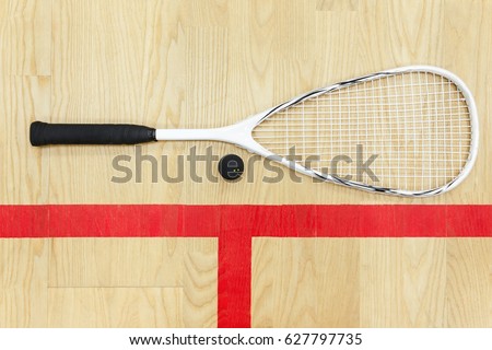 white squash racket and ball on the wooden floor top view. Racquetball equipment on the court near red line