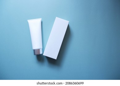 White Squeeze Bottle Plastic Tube And Box On Blue Background. Spa And Cosmetics Concept, Flat Lay, Top View. Mockup, Template.