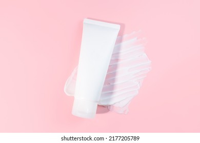 White Squeeze Bottle Plastic Tube And Moisturizer Smear Texture On Pink Background. Flat Lay, Top View. Daily Moisturizing Cream, Gel, Skin Care, Sunscreen, Lubrication. Front View, Blank, Template