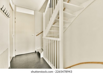 a white staircase with black tile flooring and wooden handrails in an empty house or residential apartment area - Powered by Shutterstock