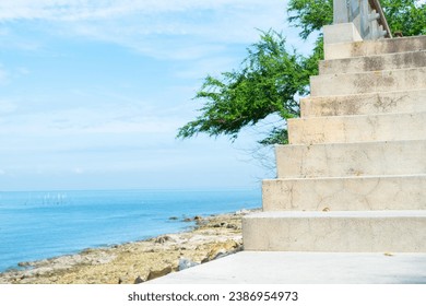 White stairs heading down to the oceanbeach as sea foam and waves roll in,waves splashes on rock in sea shore,Summer vibe concept.