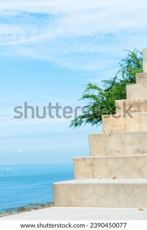 White stairs heading down to the oceanbeach as sea foam and waves roll in,waves splashes on rock in sea shore,Summer vibe concept.