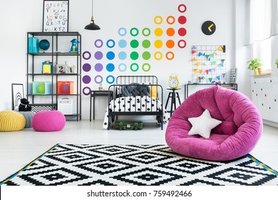 White Star Pillow On Pink Pouf In Colorful Child's Bedroom With Geometric Carpet On The Floor And Stickers On The Wall