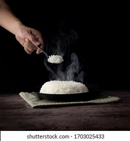 White Steam Rice With Hand Holding Spoon Eating Hot Rice Over Dark Background