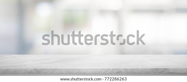 White stone marble table top and\
blurred abstract background from interior building banner\
background - can used for display or montage your\
products.