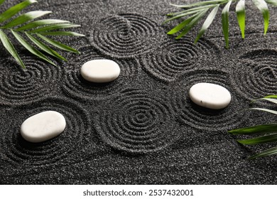 White stones and palm leaves on black sand with lines. Zen concept - Powered by Shutterstock