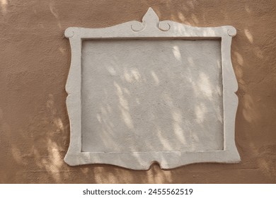 White street name sign, empty place for text, logo. Decorative architectural detail, frame or border. Old beige textured building, house wall in sunlight. Road sign. Mock up signboard. Copy space.
