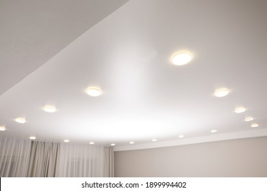 White stretch ceiling with spot lights in room - Shutterstock ID 1899994402