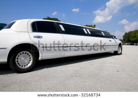 White stretch limousine with partly cloudy blue sky