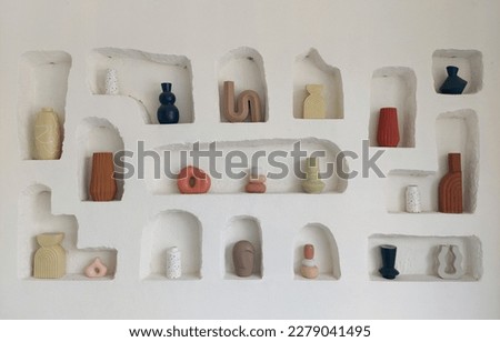 White stucco decorative wall open niche filled with ceramics display of clay pottery and abstract clay kitchenware. Stucco wall is commonly used in outdoor cafe or ancient building for its nature.