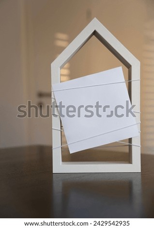 White, stylised house indoors with free note and space for text