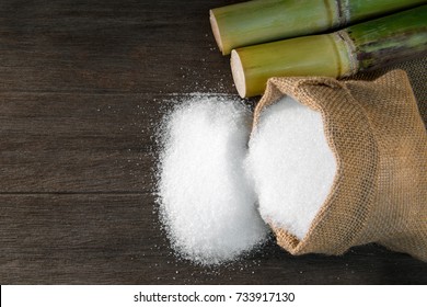 White Sugar, Sugar in bag sack with Fresh green sugar cane cut on wooden background, top view with copy space for your text message or promotional content.