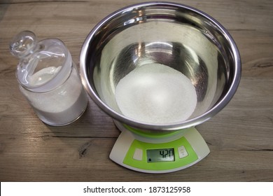 White sugar in a bowl on the scales on the wood background. the first step for making muffins, pie, biscuit. baking process step by step. 420 grams of sugar. weighing products on electronic scales.
