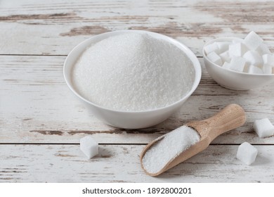 White Sugar Crystals And Cubes Of Refined Sugar In A Bowl On Wooden Table.