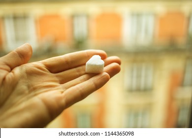 White sugar in heart shape in a woman hand