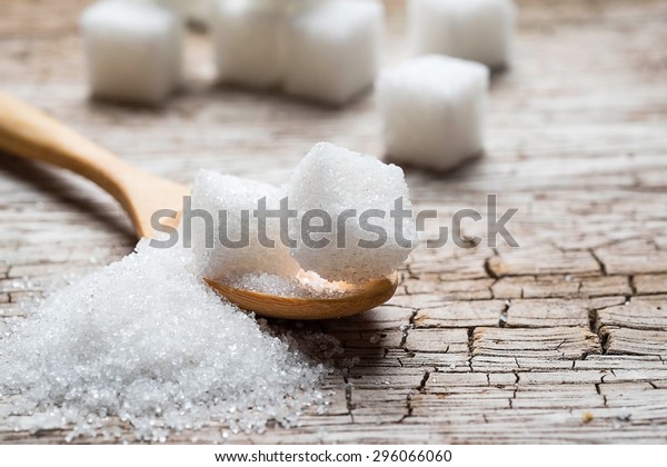 white sugar in wood\
spoon on wood table