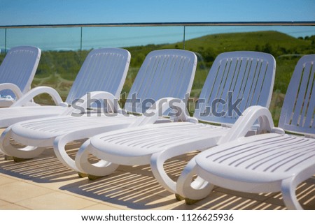 white sun loungers by the pool under the open blue sky. summer holiday. journey. rest by the sea.