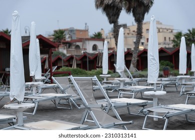 white sun loungers on the sandy city beach (sun beds and umbrellas) - Powered by Shutterstock