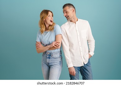 White Surprised Couple Exclaiming And Looking At Each Other Isolated Over Blue Background