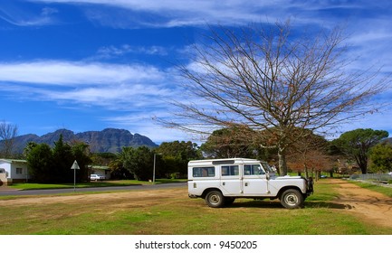 White SUV Car Under Tree - With Background Of Majestic Mountains. Shot In August, Stellenbosch, South Africa.