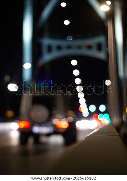 White SUV driving over large bridge\
at night. Car blurred and out of focus with many lights in\
background. Traffic on Lions Gate bridge in Vancouver,\
Canada.