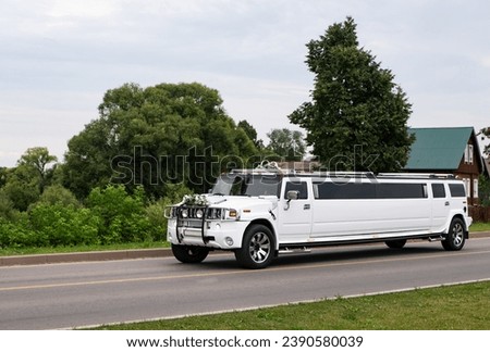 White SUV-limousine on a country road. Wedding cortege. Decorated car of the bride and groom. White Hummer limousine at a rustic wedding in provincial Russia. 