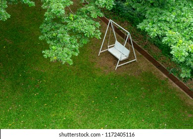 White Swing Bench Chair Under Green Tree On The Green Garden From Top View