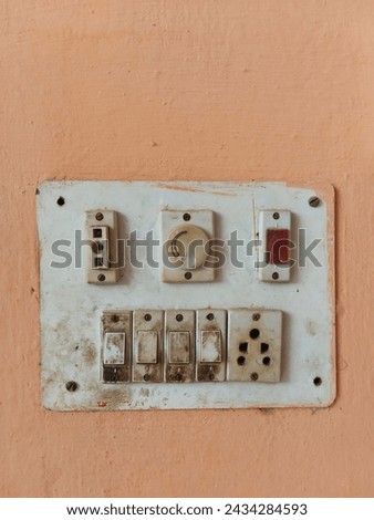 white switch board with multiple pin indian plug socket on a wall , dirty switch board