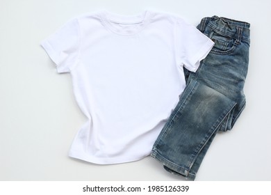 White T Shirt Mockup On White Table Background With Jean. Template, Flat Lay. Kid, Child Clothes.