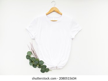 White T Shirt On Hanger With Eucalyptus Isolated On White Background. Simple White T Shirt Mock Up For Your Design
