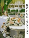 White table with chairs and a floral arrangement in the center, set up for a wedding or a special event.